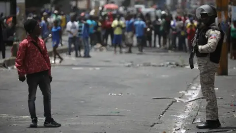 Reuters A man talks to a Haitian National Police officer guarding a commercial area that was looted during protests against fuel price increases in Port-au-Prince, Haiti, July 8, 2018.