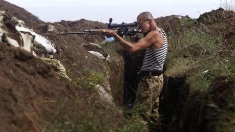 AFP A Ukrainian volunteer fighter searches for pro-Russian separatists in the village of Shyrokyne, Donetsk region on 3 July 2015