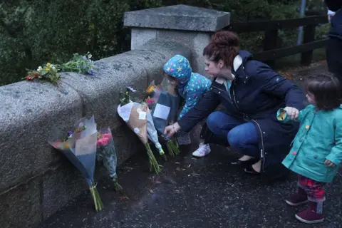 Russell Cheyne / Reuters A woman places flowers by an entrance to Balmoral Castle