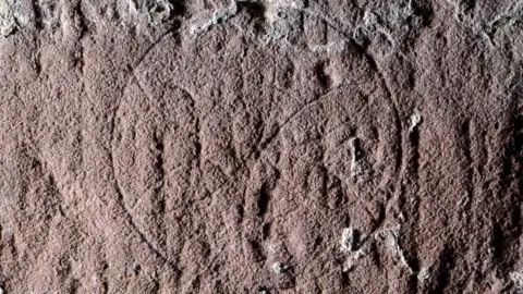 Antonia Thomas Six petalled flower mark carved in stone