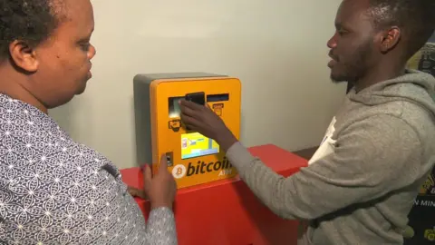 A man shows a woman how to use a cash to Bitcoin machine