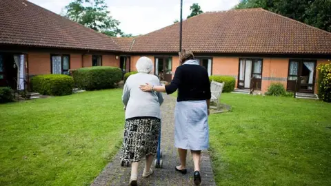 Alamy old lady and helper in residential care complex