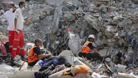 Getty Images Search and rescue work continues at debris of a building after air strikes by Israel in al-Rimal, Gaza