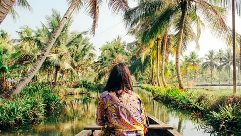 Getty Images A young woman kayaks through the backwaters of Monroe Island in Kollam District, Kerala, South India.