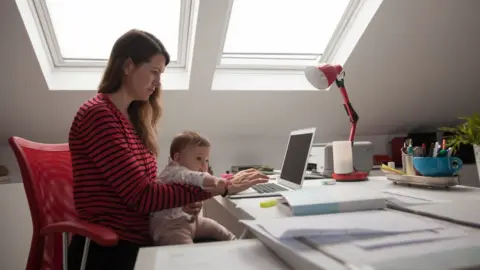 Getty Images Woman working from home with baby.