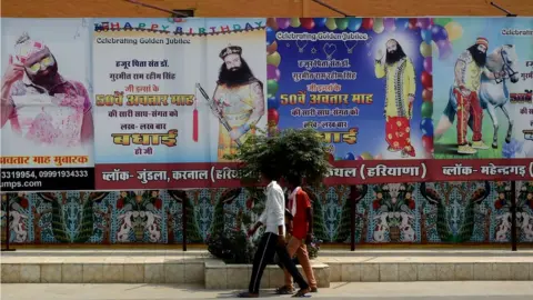 Getty Images In this photo taken on August 27, 2017 followers of the controversial Indian guru Ram Rahim Singh walk outside the 'Dera Sacha Sauda' ashram in Sirsa.