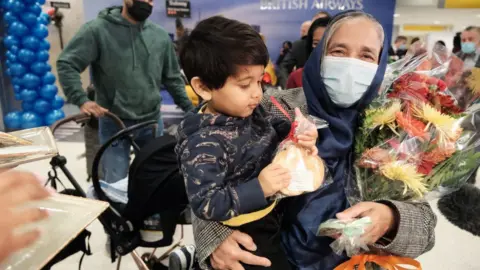 Getty Images Kushnahar Begum is re-united with her grandson as passengers arrive from the first British Airways flight to arrive since the U.S. lifted pandemic travel restrictions on November 08, 2021 in New York City.