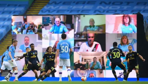 Laurence Griffiths / AFP Manchester City fans shown on a giant screen at the Etihad Stadium