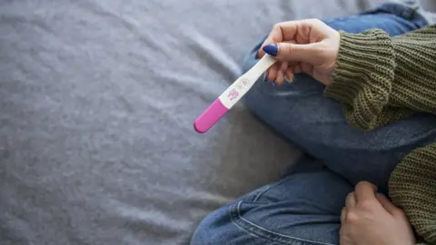 Getty Images Unrecognisable woman holding positive pregnancy test.