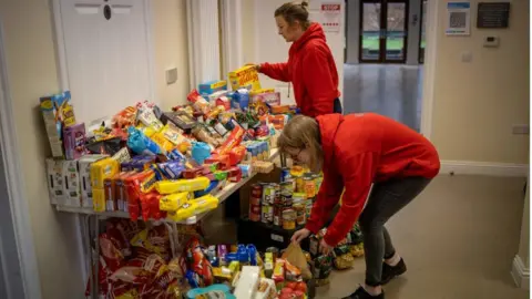 Getty Images A heaped table of food with two workers