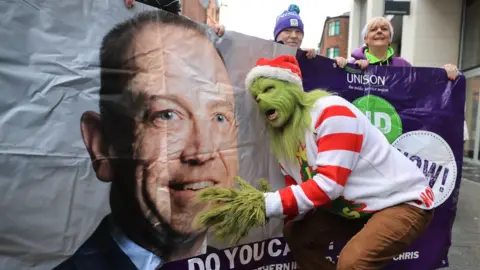 Liam McBurney/PA The Grinch with a Unison banner of Chris Heaton-Harris