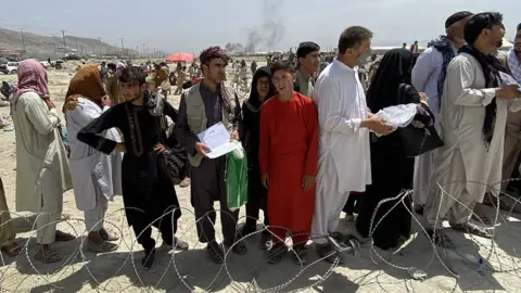 EPA Afghans including those who worked for the US, NATO, Europe Union and the United Nations in Afghanistan wait outside the Hamid Karzai International Airport to flee the country