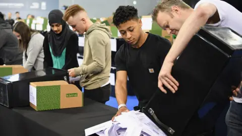 Getty Images volunteers tipping ballot papers out of box at local election count