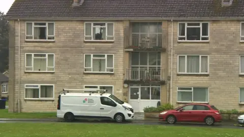 Block of flats in Rudloe. A white GreenSquare van is parked in front, next to a red car.