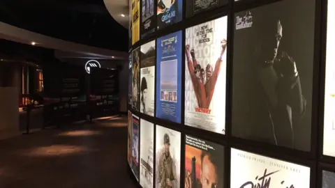 BBC A corridor inside the Empire Cinema in Ipswich with a wall covered in film posters