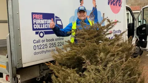 Dorothy House Hospice Volunteer in front of a large van with a Christmas tree