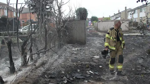 SYFRS / Twitter Firefighter walks through burnt out trees