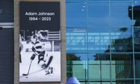 PA Media A message board shows a black and white tribute to Nottingham Panthers' ice hockey player Adam Johnson at the Motorpoint Arena in Nottingham