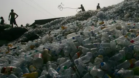 Getty Images Workers on a pile of plastic bottles in China