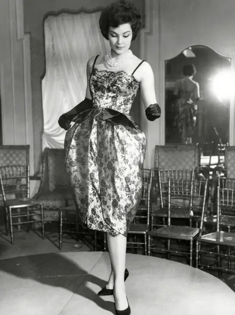 Shutterstock A model stands on a stage wearing a satin dress