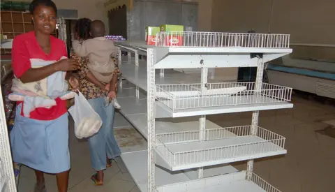 AFP JULY 4th 2007: Zimbabwean shoppers walk past empty shelves in Mabvuku, Harare, Zimbabwe. Zimbabwe's government ordered shop owners to reduce prices on all goods by 50% which has resulted in an acute shortage of most basic commodities. President Robert Mugabe has accused businesses of profiteering and working in cahoots with the country's enemies to incite people to revolt against his government.