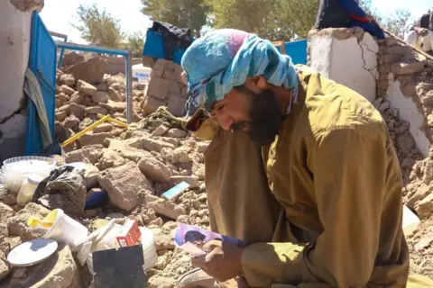 Esmatullah Habibian / AFP An Afghan man shows his family photo to the camera