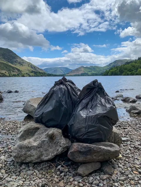 Lakes Plastic Collective Two bags of rubbish collected at the side of a lake