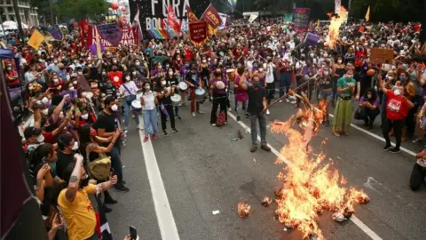 Reuters A demonstrator burns a doll representing the president