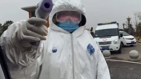 A worker checking the BBC team's temperature