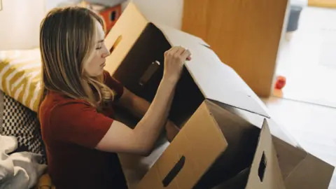 Getty Images Woman packing boxes to move house