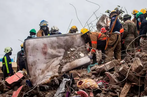 Getty Images Firefighters remove debris in search of survivors in Les Cayes, Haiti on 17 August 2021