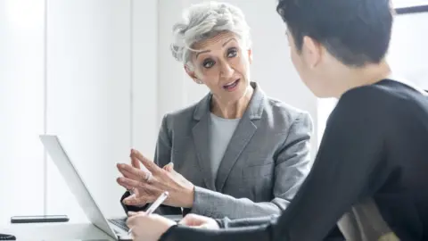 Getty Images Businesswoman talking to colleague