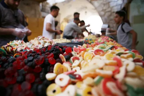 EPA Sugared treats are seen close-up with buyers and vendors in the background.