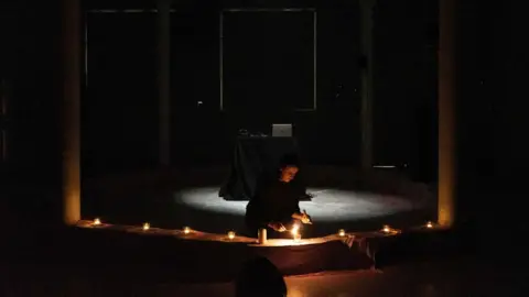 Ben Malcolmson Sinéad O'Neill-Nicholl lighting a candle as part of her live performance