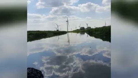 Caroline Turner Clouds and a windfarm reflected in water