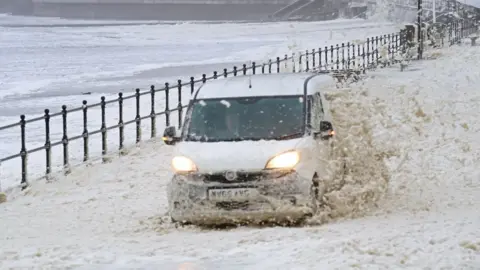 Owen Humphreys/PA Wire A van drives though the sea foam in Seaburn, Sunderland