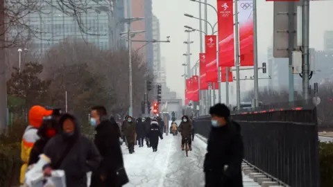 Reuters People bundled up in winter clothes walk down snow-covered streets in central Beijing