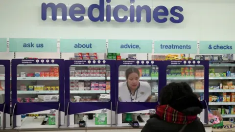 Reuters A Boots pharmacist speaking to a customer from behind a safety screen