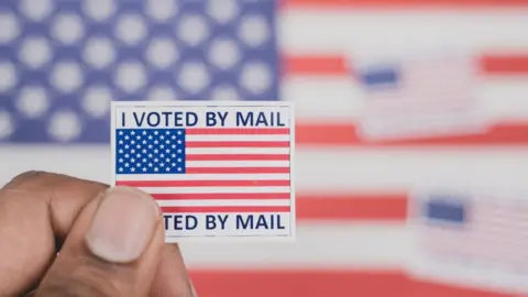 Getty Images Man holding a 'I voted by mail' sticker