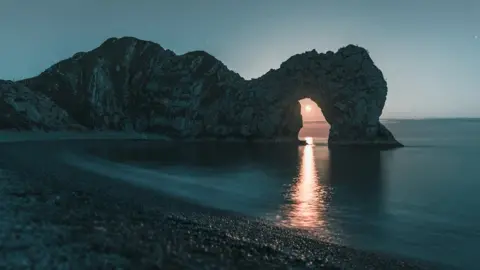 Jonathan Warner The moon through Durdle Door