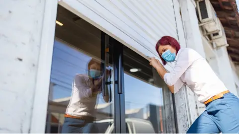 Getty Images Woman shuttering a shop