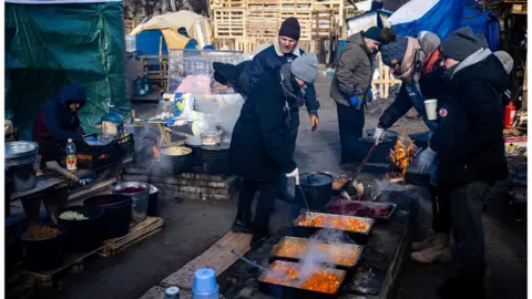 DIMITAR DILKOFF/getty images Volunteers prepare food for local residents and members of the Ukrainian Territorial Defence Forces at a field kitchen in Kyiv on 11 March 2022.