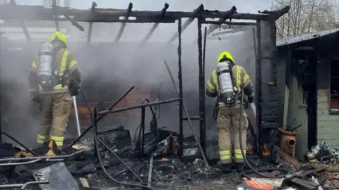 Essex Fire and Rescue Firefighters in the charred remains of an outbuilding