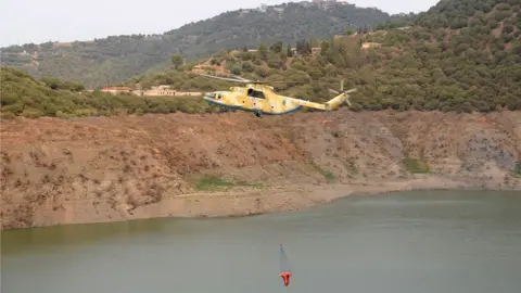 EPA An Algerian civil protection helicopter works to put out the fire in the village of Ben Douala near Tizi Ouzou, in the mountainous Kabyle region, 100 km east of Algiers, Algeria, 12 August 2021