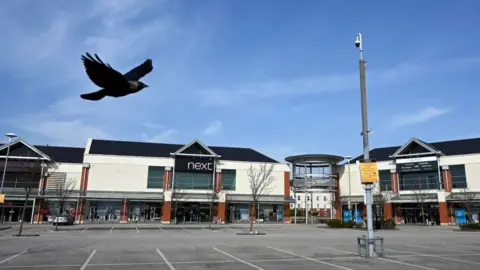 Getty Images A jackdaw flies over the carpark of a deserted retail park in Llandudno, north Wales