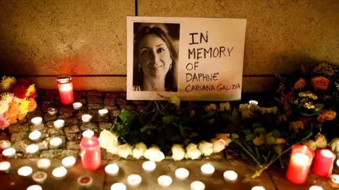 Photo of Daphne Caruana Galizia with small memorial candles lit in front.