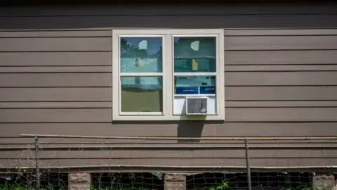 Getty Images A house with windows boarded by cardboard and with an air conditioning unit