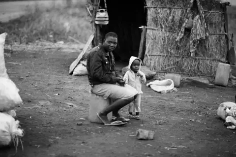 Mario Macilau Paula Cardoso next to her home