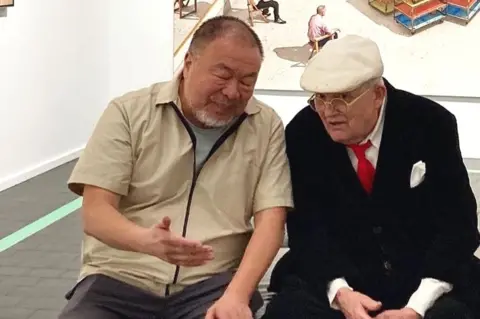 Heong Gallery Artists Ai Weiwei and David Hockney sitting in a museum