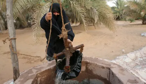 KARIM SAHIB / AFP Woman taking water from a well in Liwa, south of Abu Dhabi